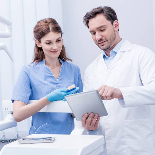 Dental assistant consulting with emergency dentist in Mesa over treatment details on a tablet